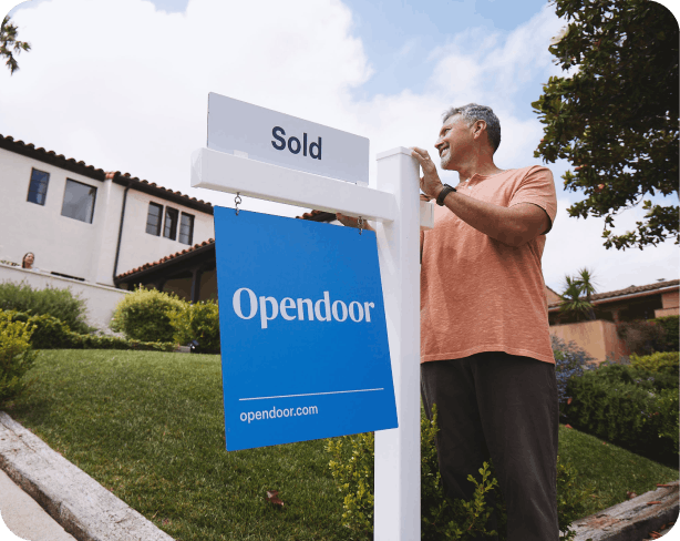 Man standing in front of his house next to a Sold sign from Opendoor. A text bubble that reads 'Moving day scheduled.'